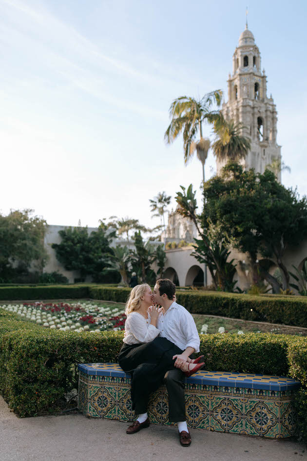 couple sitting together in front of a flower garden in san diego in balboa park