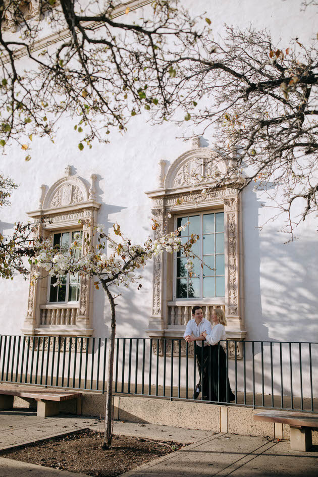 couple standing with each other by a cherry blossom tree in san diego in balboa park